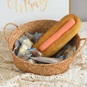 Detail of woven seagrass basket with snack packs and a plush hot dog toy on lace
