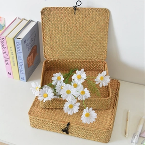 Handwoven straw storage box set with lids and elastic closures on white tabletop