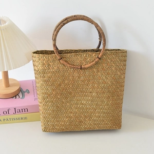 Detailansicht der handgeflochtenen Strohtasche mit runden Holzgriffen und Textur