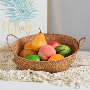 Close-up of a handmade natural seagrass storage basket with handles and faux fruit display
