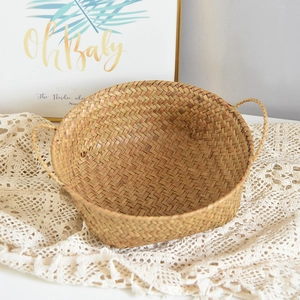 Detail of hand-woven natural seagrass storage basket with handles on white lace cloth