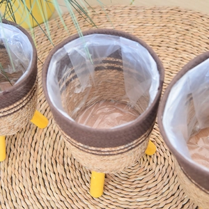 Detail of hand-woven plant basket with waterproof liner and three yellow wooden legs