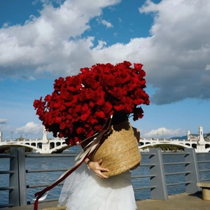 Detailed view of large red rose bouquet in a woven straw basket with decorative ribbons