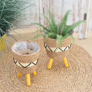 Detail of woven seagrass plant pots with geometric lines and wooden tripod legs