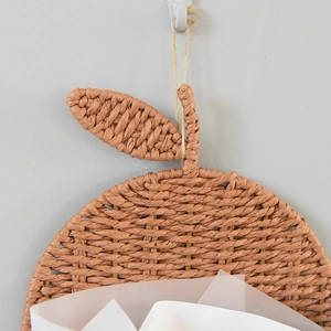 Close-up of apple-shaped woven storage basket with natural brown fibers and leaf details
