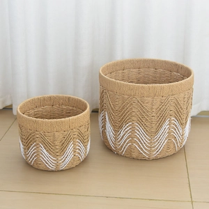Detailed close-up of two handmade woven storage baskets with white wave patterns on bottom