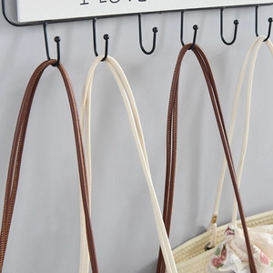 Detail of multi-functional black metal hook rack with woven bags in a home setting