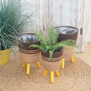 Detail of woven straw plant baskets with yellow wooden legs and waterproof inner liners