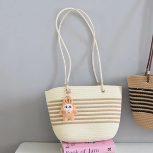 Detailed view of woven straw tote bag texture with brown stripes and plush bunny charm