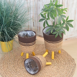 Detail view of woven plant baskets with sturdy wooden legs and waterproof inner liners