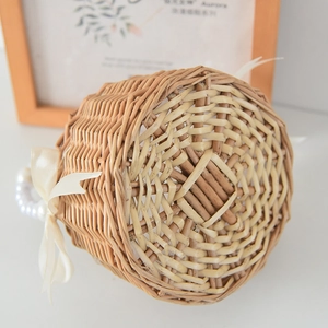 Detalle de cesta de mimbre tejida a mano con asa de perlas y lazo decorativo de cinta