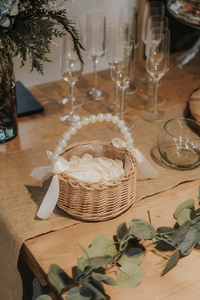 Detalle de cesta de mimbre trenzada con asa de perlas elegantes y lazos de cinta blanca