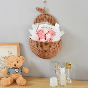 Pear-shaped hand-woven wall basket with natural plant fiber texture and pink roses
