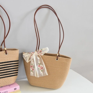 Detailed close-up of woven straw tote bag with floral lace bow and brown handles
