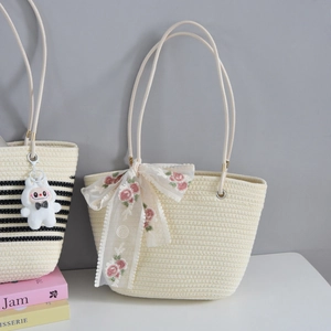 Detail of cream woven tote bag featuring floral lace bow and cartoon bunny pendant