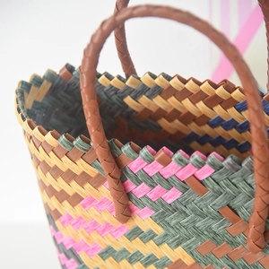 Close-up of colorful woven tote bag showing detailed texture and brown braided handles