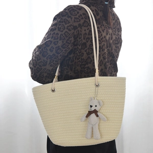 Macro view of woven straw tote bag texture and a cute knitted bear charm on the strap