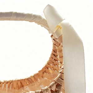 Macro detail of hand-woven wicker flower basket with white satin ribbon and bow