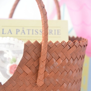 Detail of hand-woven brown tote bag featuring wavy edges and elegant lace lining detail