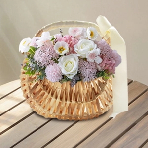 Close-up of handmade willow flower basket with silk bow and assorted floral arrangements