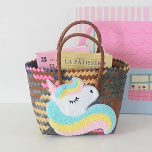 Detail of hand-woven tote bag featuring a cute pastel unicorn patch and leather-style handles