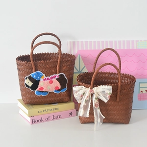 Detail of woven straw tote bags with cartoon puppy patch and white lace floral bow decoration