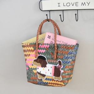 Detail of woven tote bag with a cute dachshund embroidery hanging on a gray wall