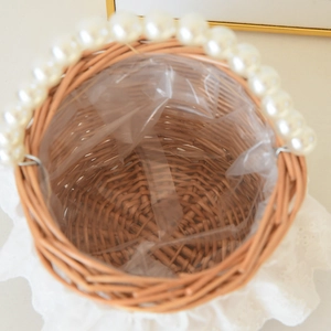 Detail of woven wicker basket with white pearl handle and lace trim with waterproof liner