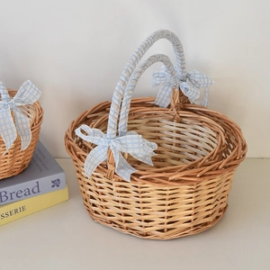 Detailed view of handmade wicker picnic basket with blue checkered bow on natural handles
