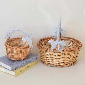 Close-up of woven wicker picnic baskets with blue and white checkered ribbon handles