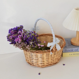 Detail of hand-woven wicker picnic basket with blue ribbon bow and purple dried flowers