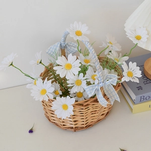 Close-up of hand-woven wicker picnic basket with blue checkered bow and white daisies