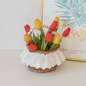 Detail of rattan picnic basket with white lace trim, faux tulips and pearl handle