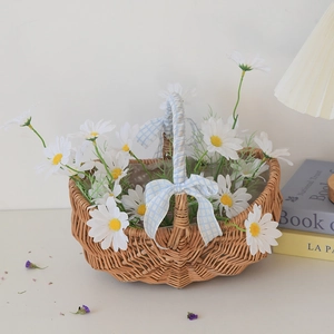 Detail of hand-woven wicker picnic basket featuring a blue checkered bow and white daisies