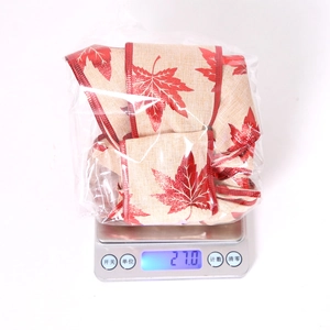 Close-up of beige linen ribbon with red maple leaf print on a digital scale