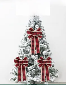 Three large red and black plaid Christmas bows with burlap edges on a snowy tree background