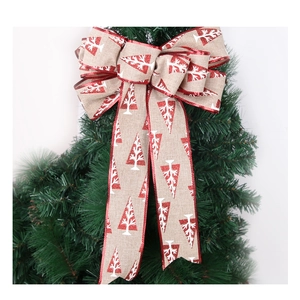 Macro detail of faux burlap Christmas bow with red glitter trim on a green pine tree