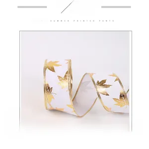 Close-up of white Christmas ribbon with gold maple leaf patterns and wire edges
