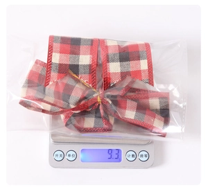 Weight display of a small red and black buffalo plaid Christmas bow for DIY crafts