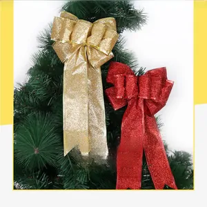 Close-up of red and gold glitter ribbon bows hanging on a green Christmas tree