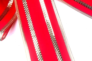 Macro detail of red velvet Christmas ribbon with embossed gold stripes and stitched edges
