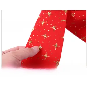 Macro detail of red velvet Christmas bow with gold glitter stars for tree decoration