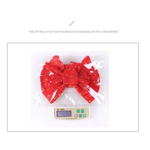 Detail view of a 32g red velvet Christmas bow with gold stars in plastic packaging