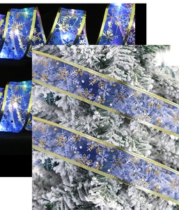 Detail of blue LED Christmas ribbon with gold snowflakes wrapped on a tree