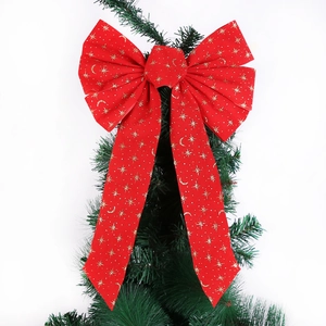 Red velvet Christmas bow with gold stars on a pine branch for festive tree decoration