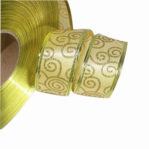 Dettaglio del nastro natalizio beige con vortici di glitter dorati e bordi metallici