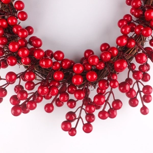 Close-up of vibrant red berry Christmas wreath on brown vine base for festive decor