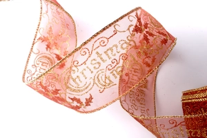 Macro shot of peach organza Christmas ribbon with golden edges and festive greetings