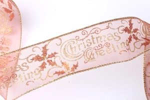 Macro detail of pink organza Christmas ribbon with golden greeting print and wire edges