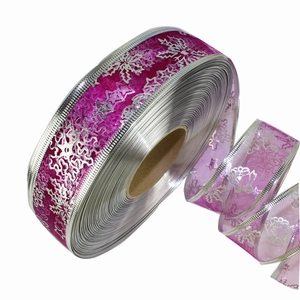 Rose red Christmas ribbon with silver snowflake and star patterns on a paper spool